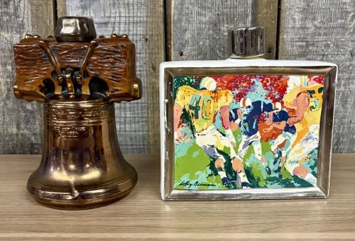 Two Ceramic Commemorative Decanters Including LeRoy Neiman Football and Liberty Bell: This lot features two vintage ceramic commemorative decanters. The first is a limited edition LeRoy Neiman Great American Sports series decanter, identified on the reverse as the third and final in a 