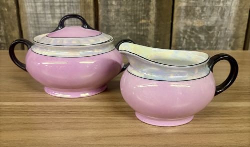 A Pair of Aich Czechoslovakia Art Deco Porcelain Lusterware Sugar Bowl and Creamer: This matching two-piece set consists of a lidded sugar bowl and a creamer, manufactured by the Aich porcelain factory in Czechoslovakia. Both pieces are crafted from porcelain and feature a vibrant pi