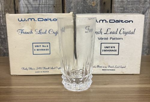 A Pair of W.M. Dalton French Lead Crystal Beverage Glasses in the Vérité Pattern: This lot features a pair of highball style beverage glasses produced by W.M. Dalton in the Vérité pattern. Each glass is constructed from finely blown 24% lead crystal, as confirmed by the original 