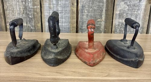 Collection of Four Antique Cast Iron Sad Irons: Collection of four fixed-handle cast iron sad irons. These tools are manufactured from solid cast iron, typical of domestic laundry equipment from the late 19th to early 20th century. The group includ