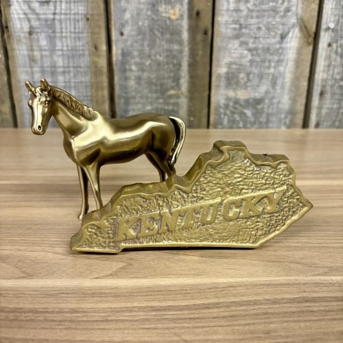 Two Decorative Brass-Toned Metal Items Including a Fritz Brass Kentucky State Paperweight and a: This lot contains two brass-toned metal decorative objects. The first is a state of Kentucky souvenir paperweight by Fritz Brass. The piece features raised, polished lettering of the word KENTUCKY set
