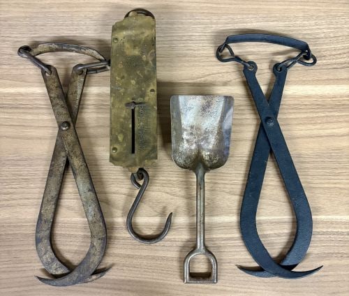 A Collection of Antique Industrial and Utilitarian Hand Tools: An assortment of antique utilitarian hand tools including two pairs of tongs, a spring balance scale, and a small hand shovel. The two pairs of tongs are of cross-hinged forged iron construction with 