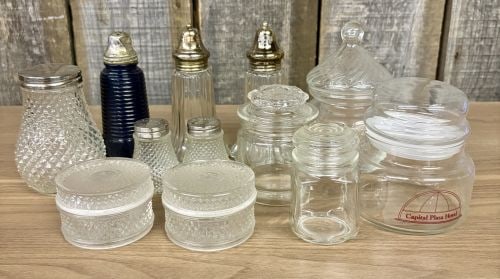 A Collection of Vintage Clear and Cobalt Blue Glass Salt and Pepper Shakers, Dresser Jars, and: An assortment of vintage glass utility and decorative items, featuring salt and pepper shakers, dresser jars, and condiment containers. The collection is primarily composed of clear pressed glass, wit