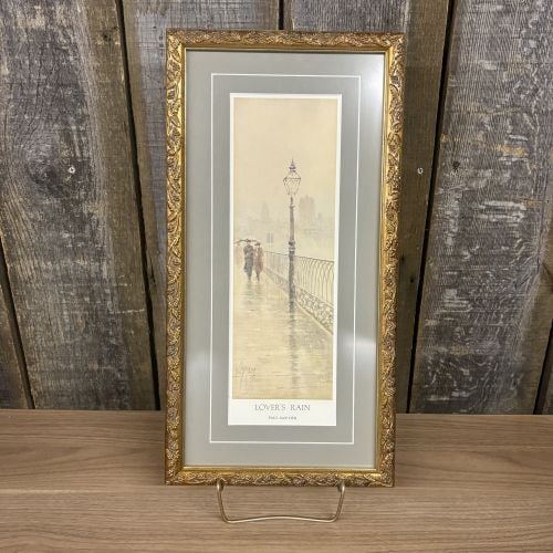Paul Sawyier, Lover’s Rain, Limited Edition Framed Print: This is a limited edition collector print titled Lover’s Rain by Kentucky artist Paul Sawyier (1865-1917). The vertical photomechanical reproduction depicts a couple walking under an umbrella across