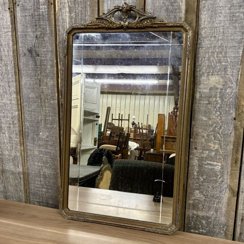 French Louis Philippe Style Giltwood and Gesso Wall Mirror: This wall mirror is designed in the French Louis Philippe style and features a rectangular frame with canted upper corners. The frame is constructed of wood with a molded gesso finish and gilt surfaci