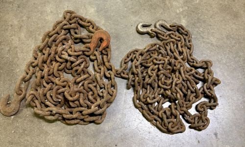 Two Heavy-Duty Industrial Rigging Chains with Columbus McKinnon Hooks: This lot consists of two heavy-gauge steel industrial chains designed for lifting or towing. The first set is a single-leg chain with grab hooks at each terminal end; one hook shows trace remnants of 