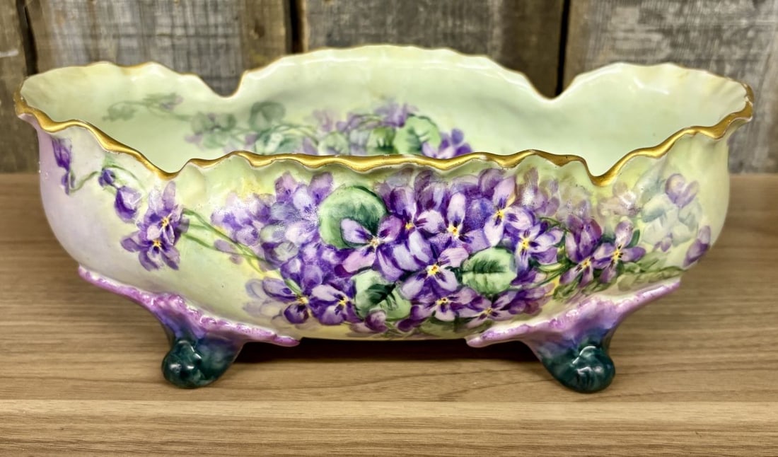 Large Hand Painted Porcelain Footed Centerpiece Bowl with Violets: This is a large, oval-shaped porcelain centerpiece bowl or low jardiniere featuring hand-painted floral decoration. The exterior and interior are decorated with clusters of purple violets with yellow 