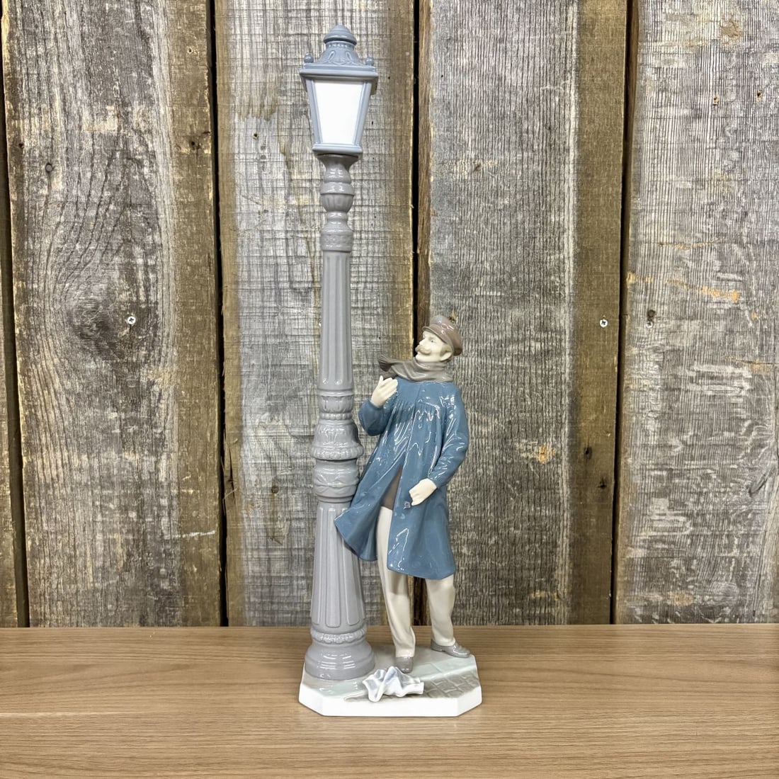 Lladro Glazed Porcelain Figurine The Lamplighter Model 5205: A LladrÛ glazed porcelain figurine titled The Lamplighter (El Farolero), model number 5205, designed by Salvador FuriÛ. The figurine depicts a man dressed in early 20th-century attire, including a b