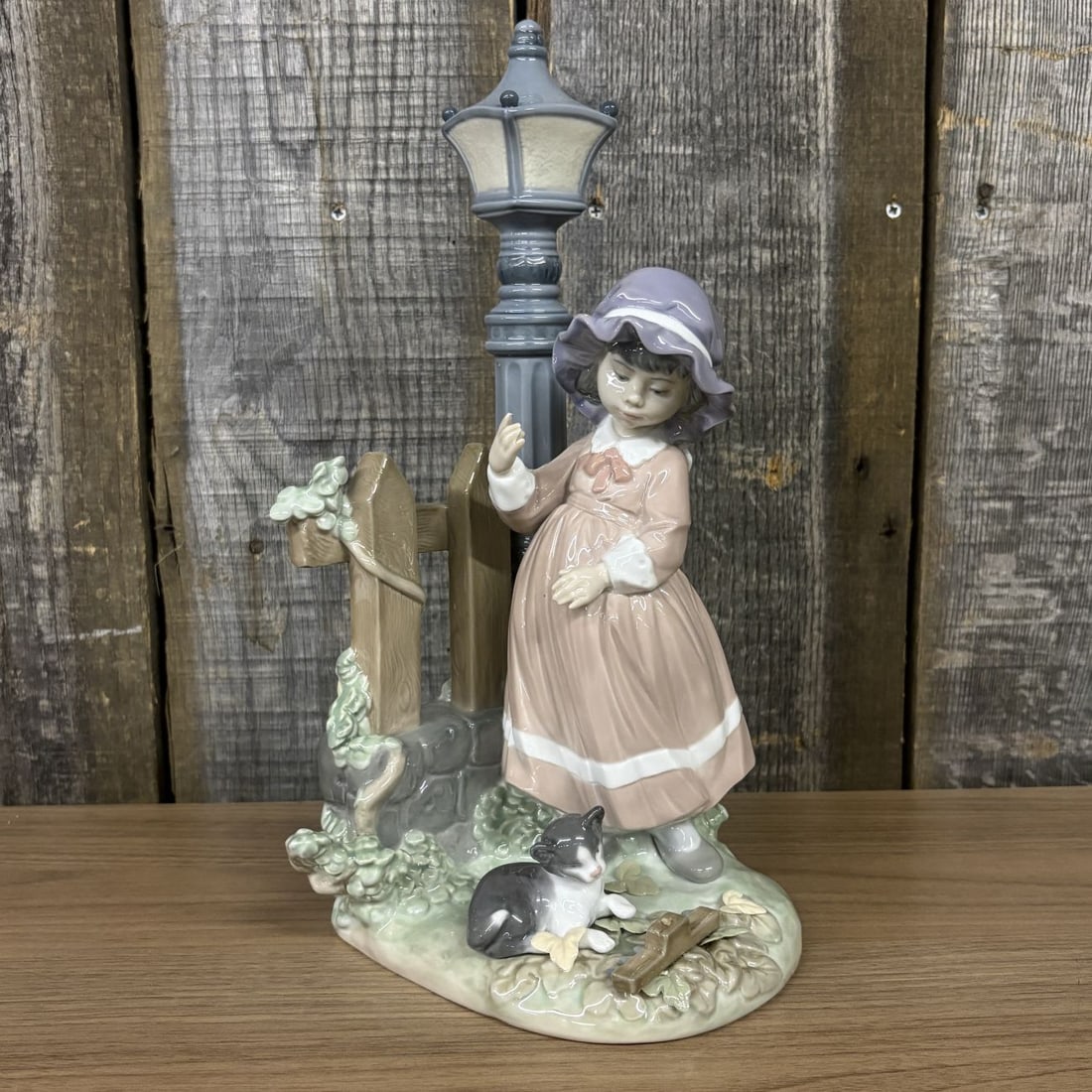 Lladro Fall Clean Up Porcelain Figurine Model 5286: Lladro glazed porcelain figurine titled Fall Clean Up, model number 5286. The sculpture depicts a young girl dressed in a pinkish-brown long-sleeved dress featuring a white collar and a white band at 