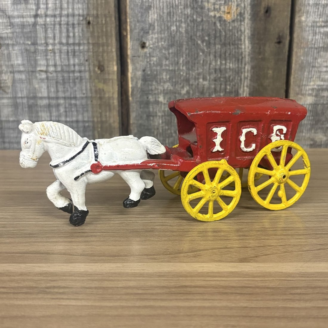 Horse-Drawn Ice Delivery Wagon Toy: This vintage horse-drawn delivery wagon is constructed of cast iron. The toy features a red-painted wagon body with an open rear compartment and the word ICE embossed in white capital letters on each 