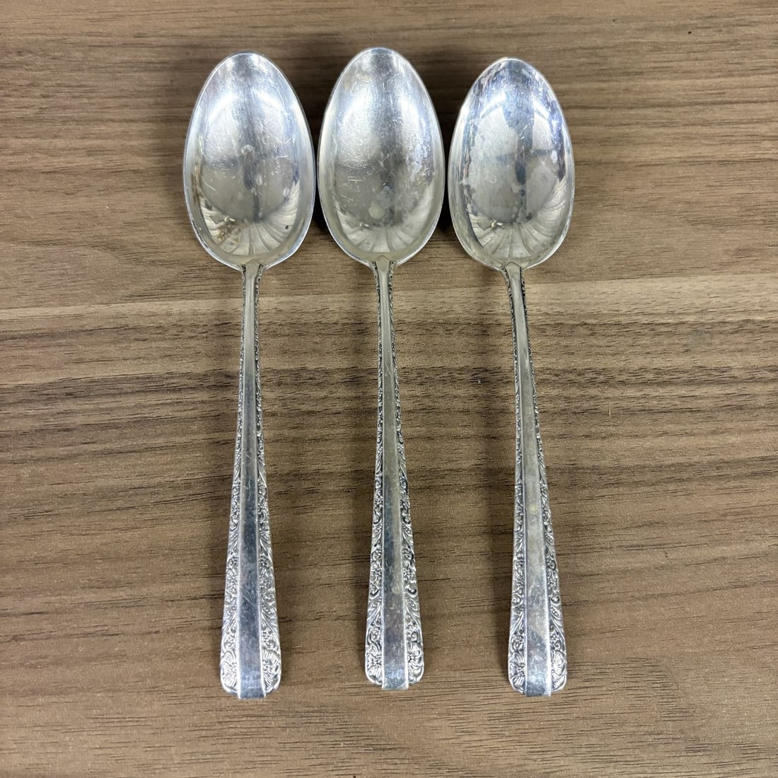A Trio of Towle Sterling Silver Teaspoons in the Candlelight Pattern: A group of three sterling silver teaspoons manufactured by Towle Silversmiths in the Candlelight pattern, which was first introduced in 1934. The teaspoons feature oval bowls and handles decorated wit