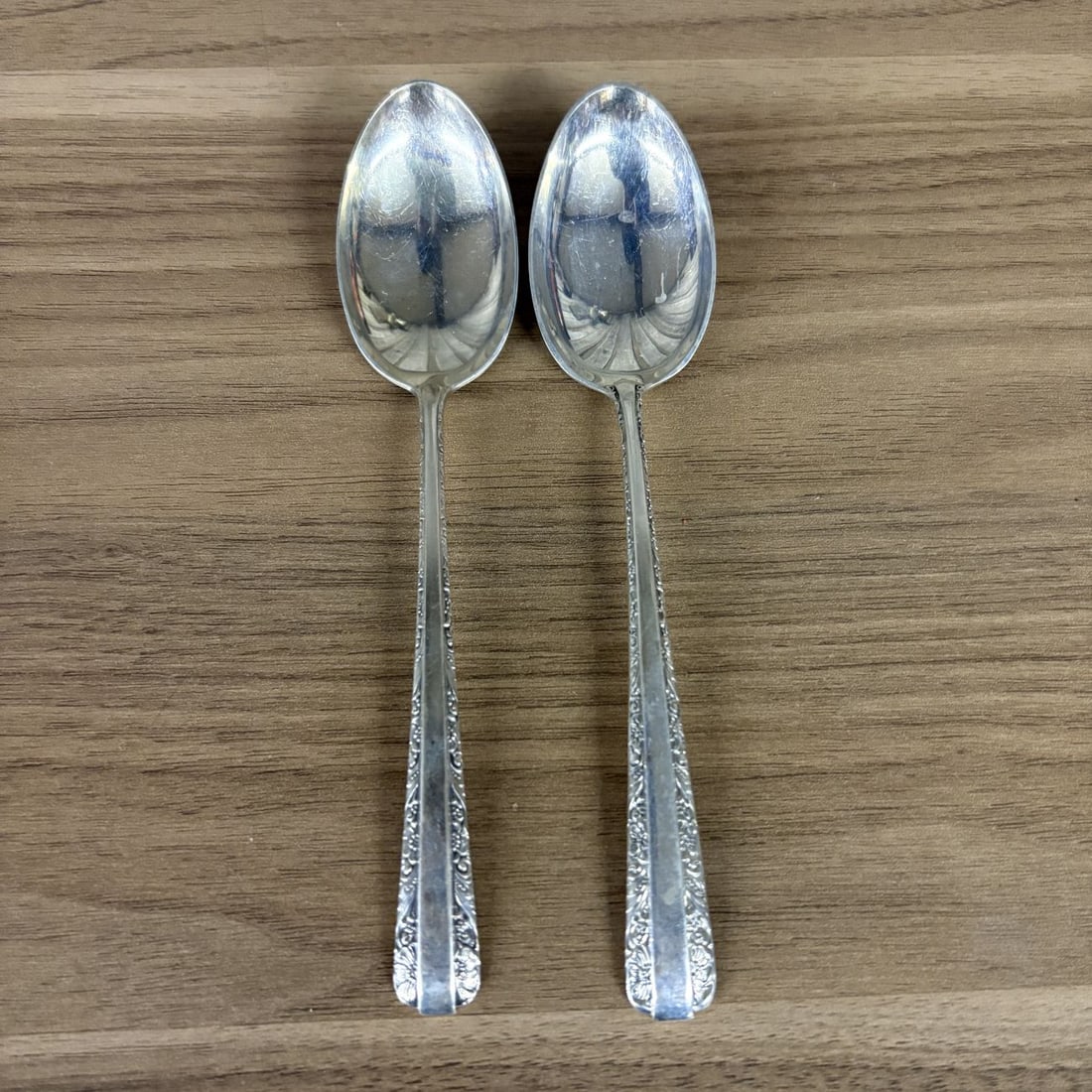 A Pair of Towle Sterling Silver Bouillon Spoons in the Candlelight Pattern: A pair of sterling silver bouillon spoons produced by Towle Silversmiths in the Candlelight pattern. The pattern, first patented in 1934, features a scrolled and floral border along the handles with a