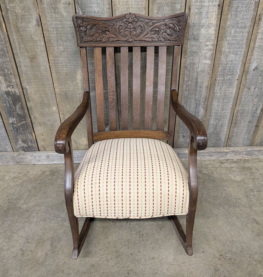 American Victorian Quartersawn Oak North Wind Face Rocking Chair: This rocking armchair is constructed from quartersawn oak, showcasing the distinct ray fleck or tiger oak grain pattern characteristic of the period. The high back features a decorative crest rail han