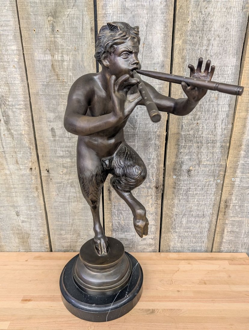 Large Bronze Sculpture of a Dancing Faun Playing the Double Flute: This large bronze sculpture depicts a dancing faun or satyr, often identified as the Greek god Pan, in a dynamic, one-legged pose while playing an aulos or double flute. Rendered in the neoclassical s