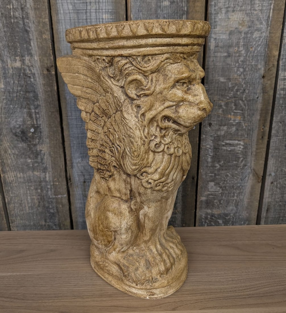 Cast Resin Winged Lion of Saint Mark Pedestal Sculpture: This pedestal sculpture is constructed of cast resin with a faux-antique finish. The piece is modeled after the iconography of the Winged Lion of Saint Mark, featuring a seated leonine figure with upr