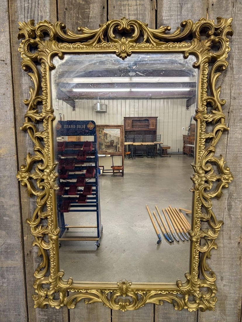 Large Rococo Style Gold Tone Molded Resin Wall Mirror: A large wall mirror in the Rococo Revival style featuring a decorative rectangular frame. The frame is constructed of molded resin with a gold-tone painted finish, characterized by elaborate pierced s