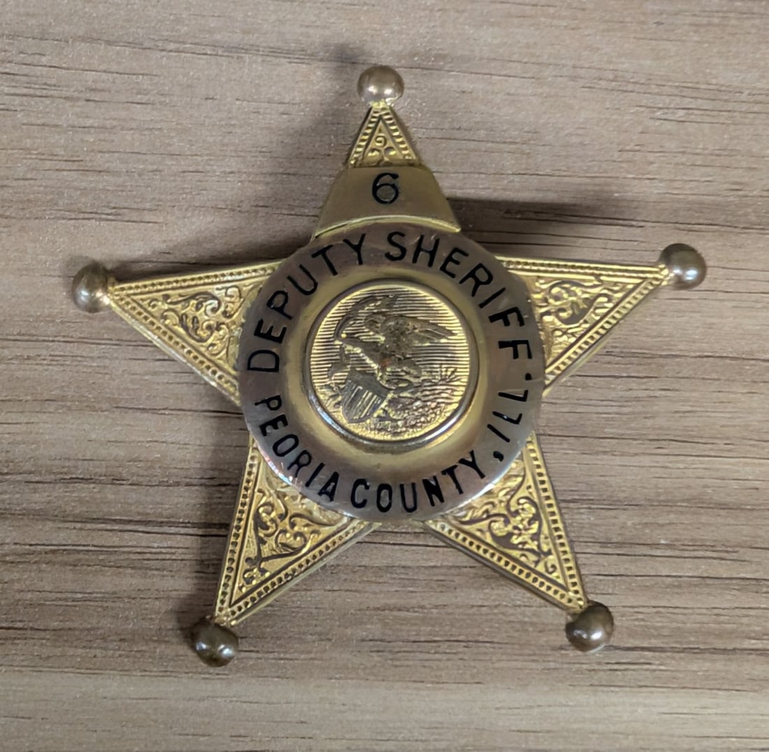 Vintage Peoria County Illinois Deputy Sheriff Five Point Star Badge Number 6: A vintage five-point star law enforcement badge issued to a Deputy Sheriff of Peoria County, Illinois. The badge is constructed from die-struck stamped brass with a gold-toned finish. Each point of th