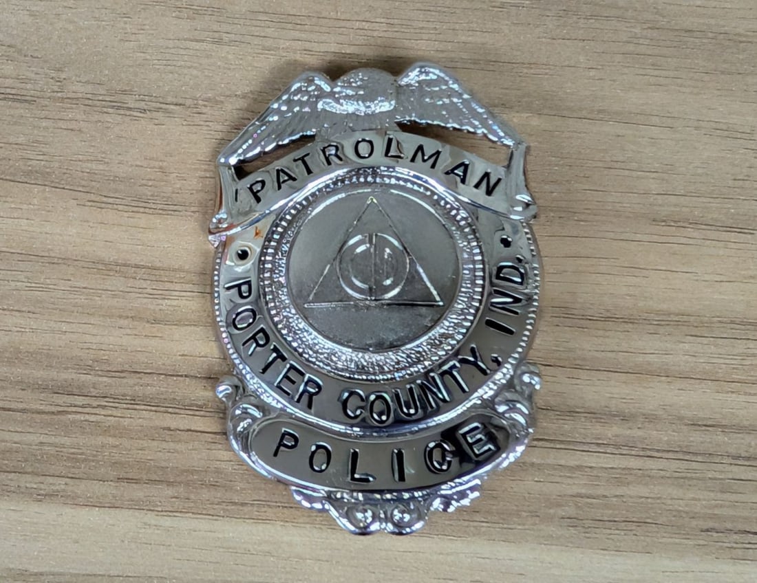 Porter County Indiana Civil Defense Patrolman Police Badge: A law enforcement badge for the Porter County Police in Indiana. This badge is designated for the rank of Patrolman. The center seal features the emblem of the United States Civil Defense, characteriz