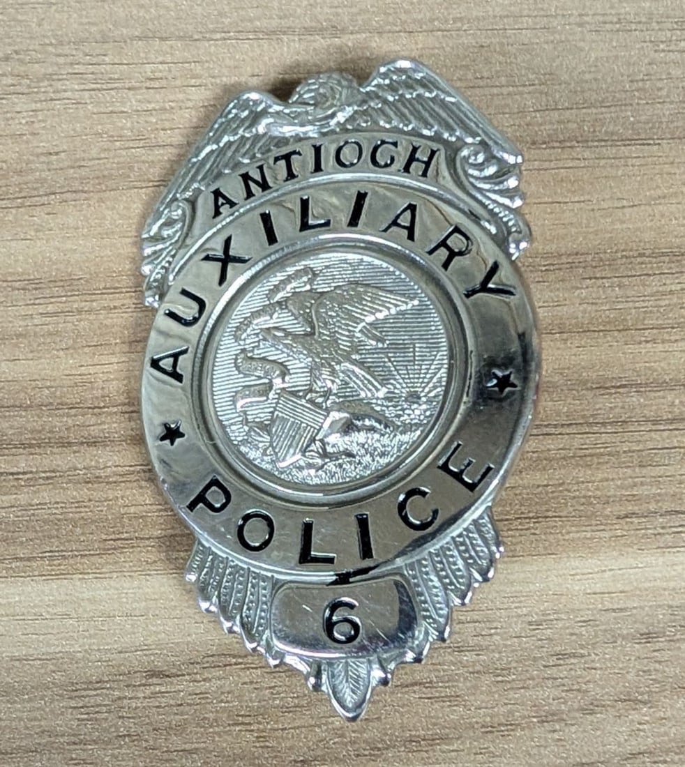 C.H. Hanson Antioch Auxiliary Police Badge Number 6: A mid-20th-century auxiliary police badge from Antioch, Illinois, manufactured by the C.H. Hanson Company of Chicago. The badge is constructed from nickel-plated base metal and features an eagle-top s