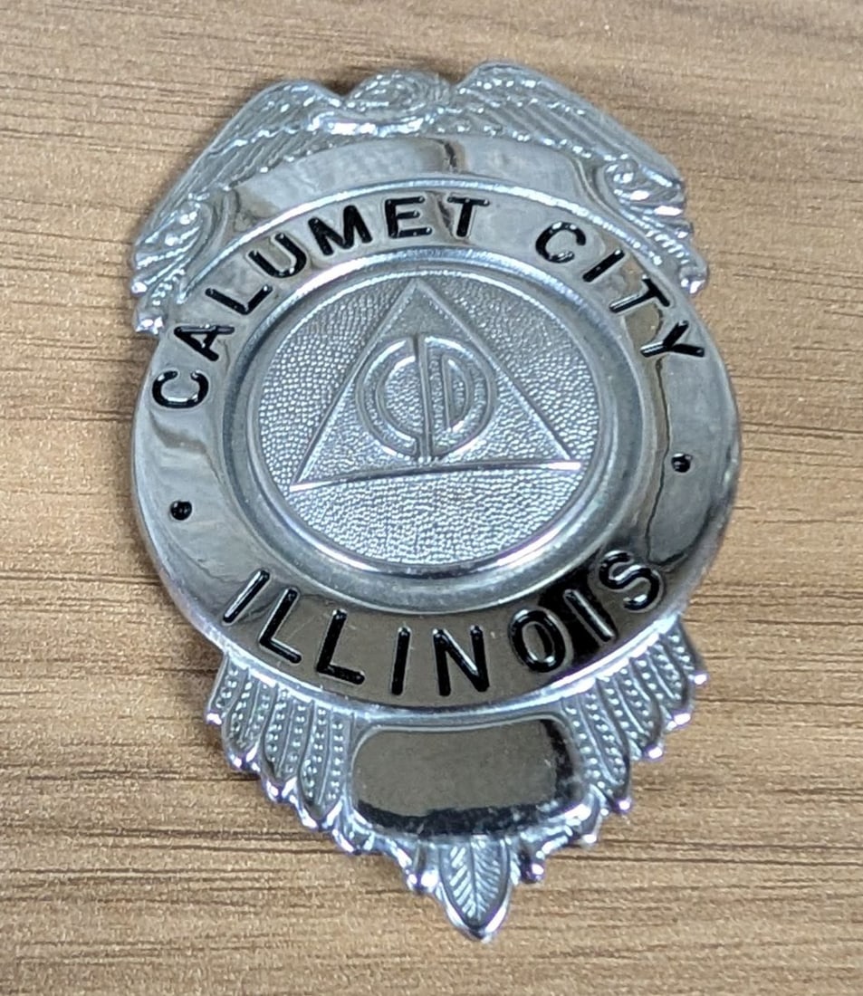 Cold War Era Calumet City Illinois Civil Defense Badge by C.H. Hanson: A mid-20th-century municipal Civil Defense badge from Calumet City, Illinois, manufactured by The C.H. Hanson Company of Chicago. The shield-shaped badge is constructed from chrome-plated white metal 