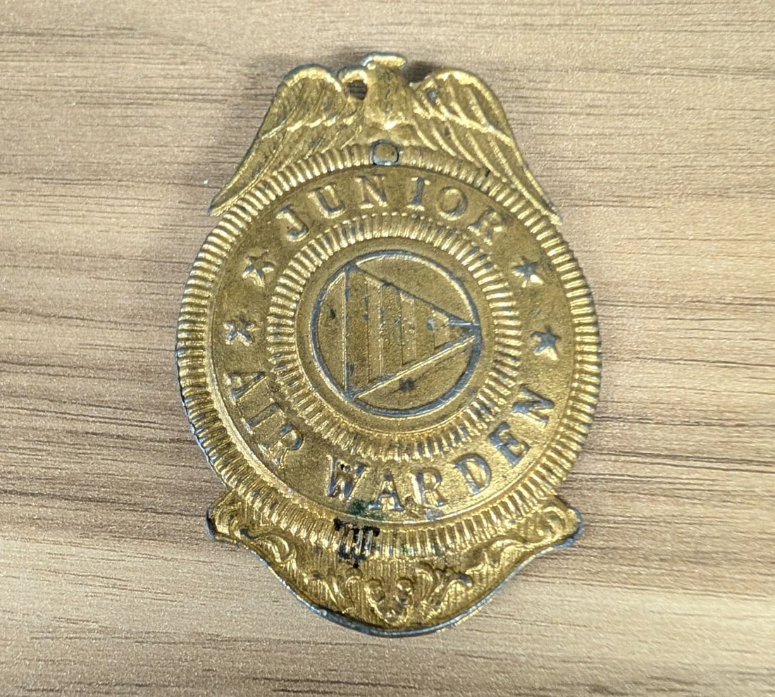 US WWII Civilian Defense Junior Air Warden Badge: This is a World War II era Junior Air Warden badge, issued to youth participants in United States Civilian Defense programs during the mid-1940s. The badge is constructed of a gilt-washed base metal, 