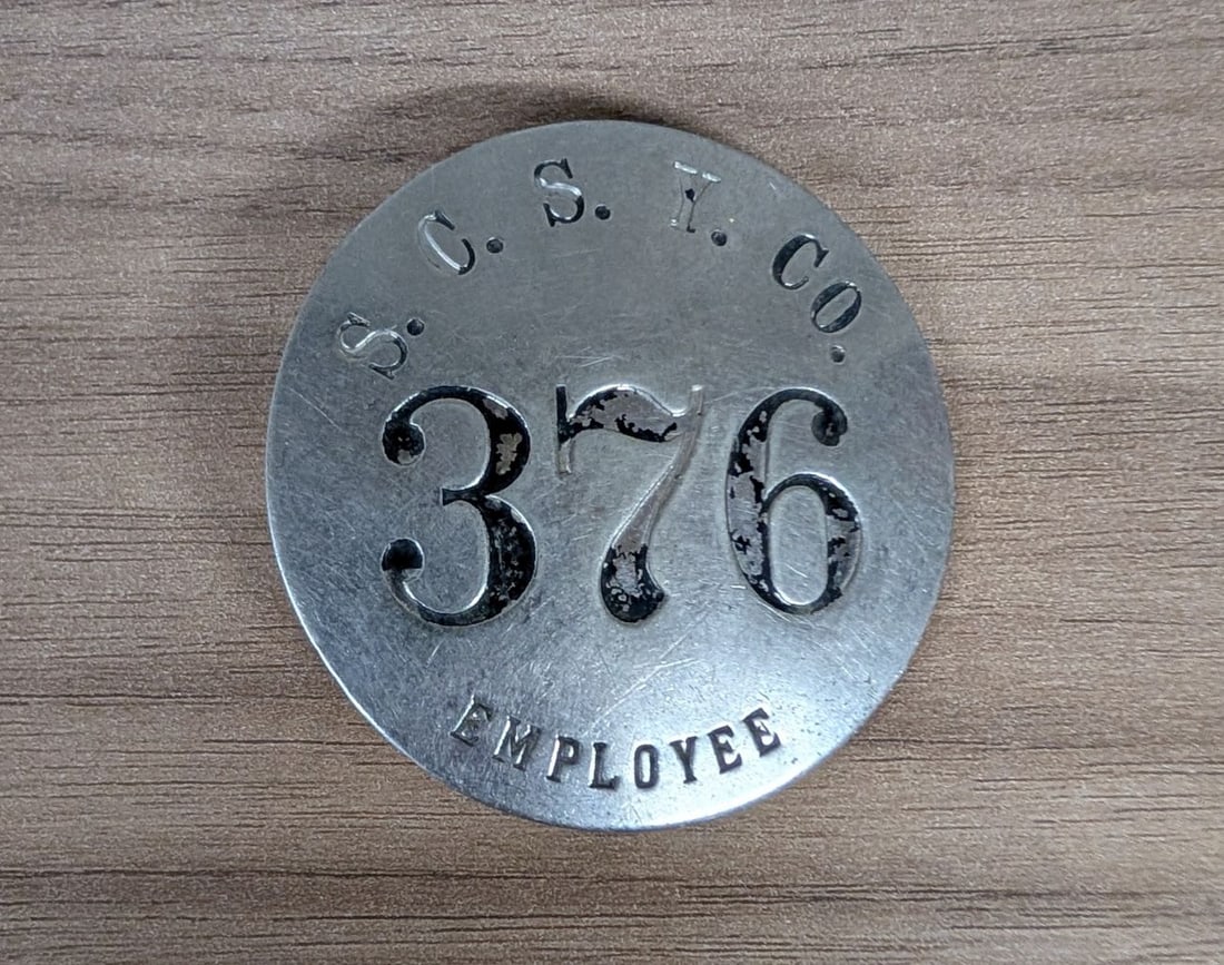 Sioux City Stock Yards Company Metal Employee Identification Badge Number 376: A circular employee identification badge issued by the Sioux City Stock Yards Company (S.C.S.Y. CO.). The piece is constructed from die-stamped, silver-toned metal, likely nickel-plated brass. The obv