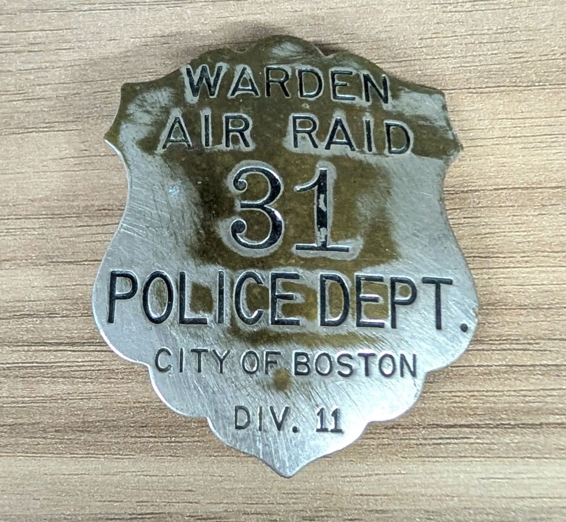 WWII City of Boston Police Department Air Raid Warden Badge Number 31 Division 11: A World War II era civilian defense badge issued by the City of Boston Police Department for the Air Raid Warden service. This shield-shaped, die-struck metal badge features recessed lettering with a 