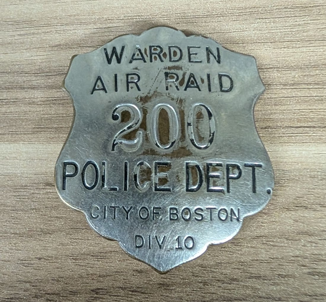 WWII Boston Police Air Raid Warden Badge Number 200 Division 10: This is an authentic World War II era Air Raid Warden badge issued by the City of Boston Police Department. The badge is constructed of stamped metal in a shield form with a scalloped top edge. The ob