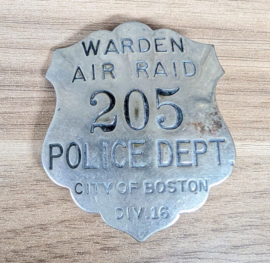 WWII Boston Police Department Air Raid Warden Badge No. 205: A die-struck shield-style badge issued to a civilian air raid warden by the City of Boston Police Department during World War II. The badge is constructed from nickel-plated base metal featuring reces
