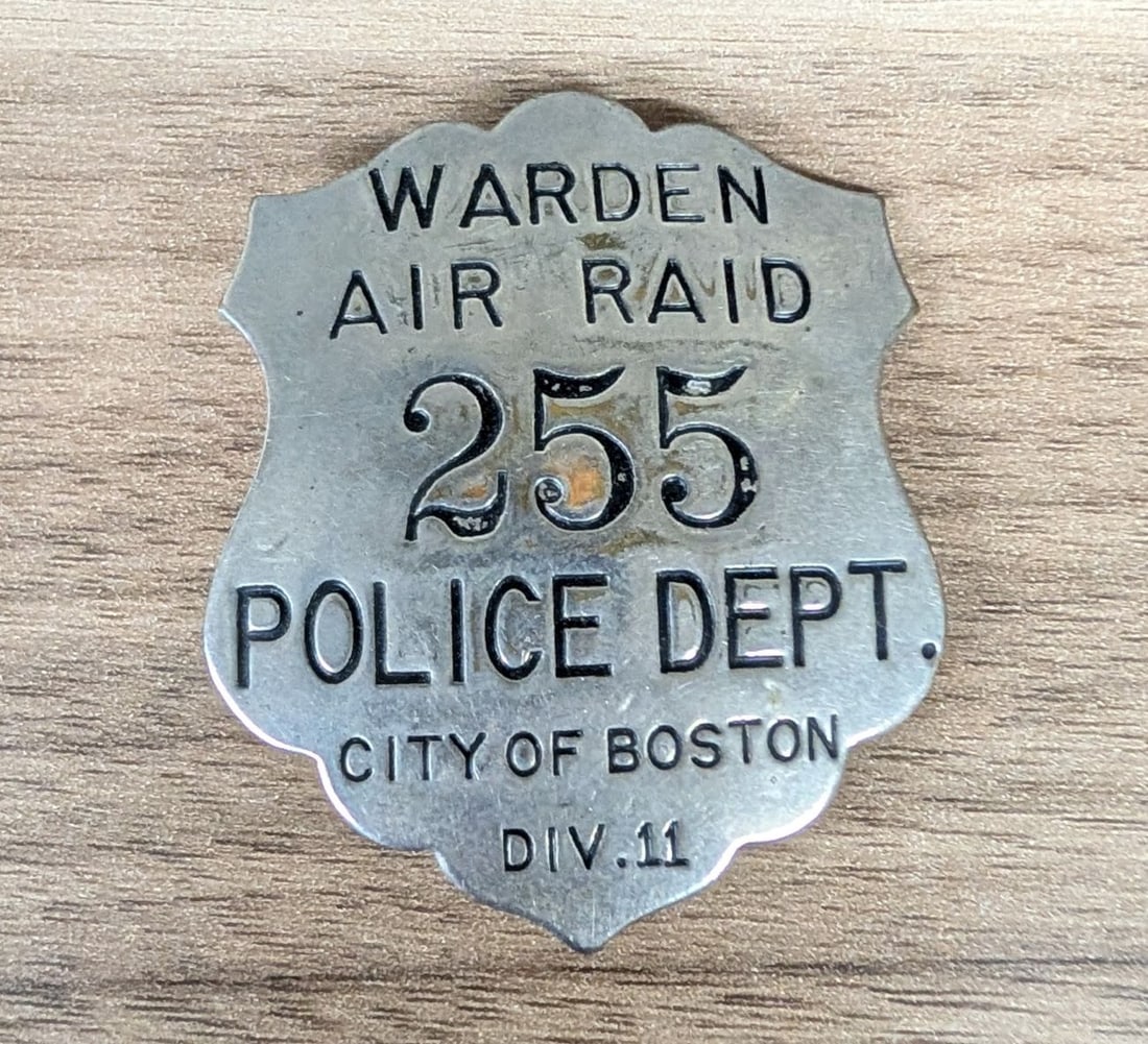 WWII Boston Police Department Air Raid Warden Badge Division 11: A World War II era Civil Defense Air Raid Warden badge issued by the City of Boston Police Department. The badge is shield-shaped with decorative scalloped edges and is constructed from a non-magnetic
