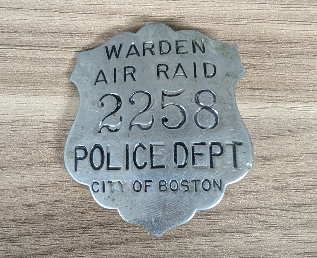 WWII Boston Police Department Air Raid Warden Badge Number 2258 Mitchell Boston: A World War II-era Civil Defense badge for an Air Raid Warden serving with the City of Boston Police Department. The shield-shaped badge is struck in a silver-toned base metal with scalloped top and b