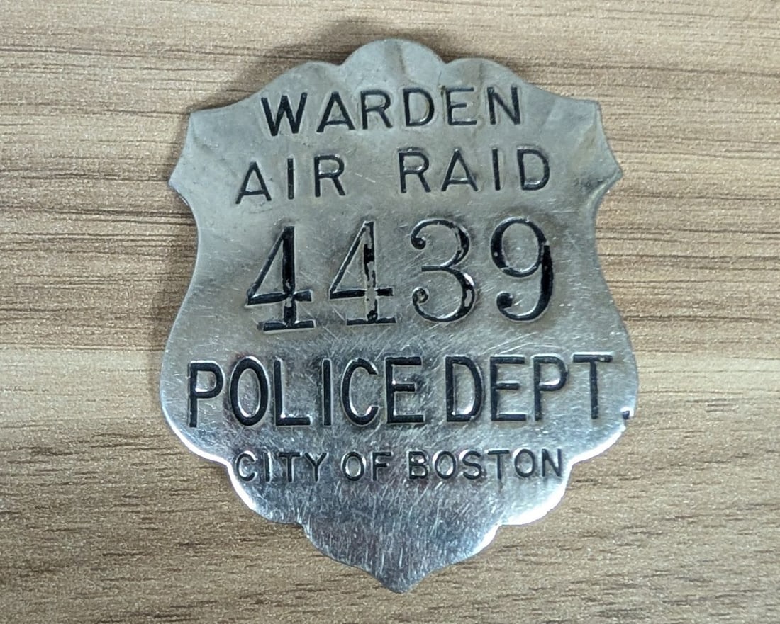 WWII City of Boston Police Department Air Raid Warden Badge Number 4439: A World War II era civilian defense badge issued by the City of Boston Police Department for the Air Raid Warden service. This shield-shaped badge is constructed from a die-stamped white metal with a 