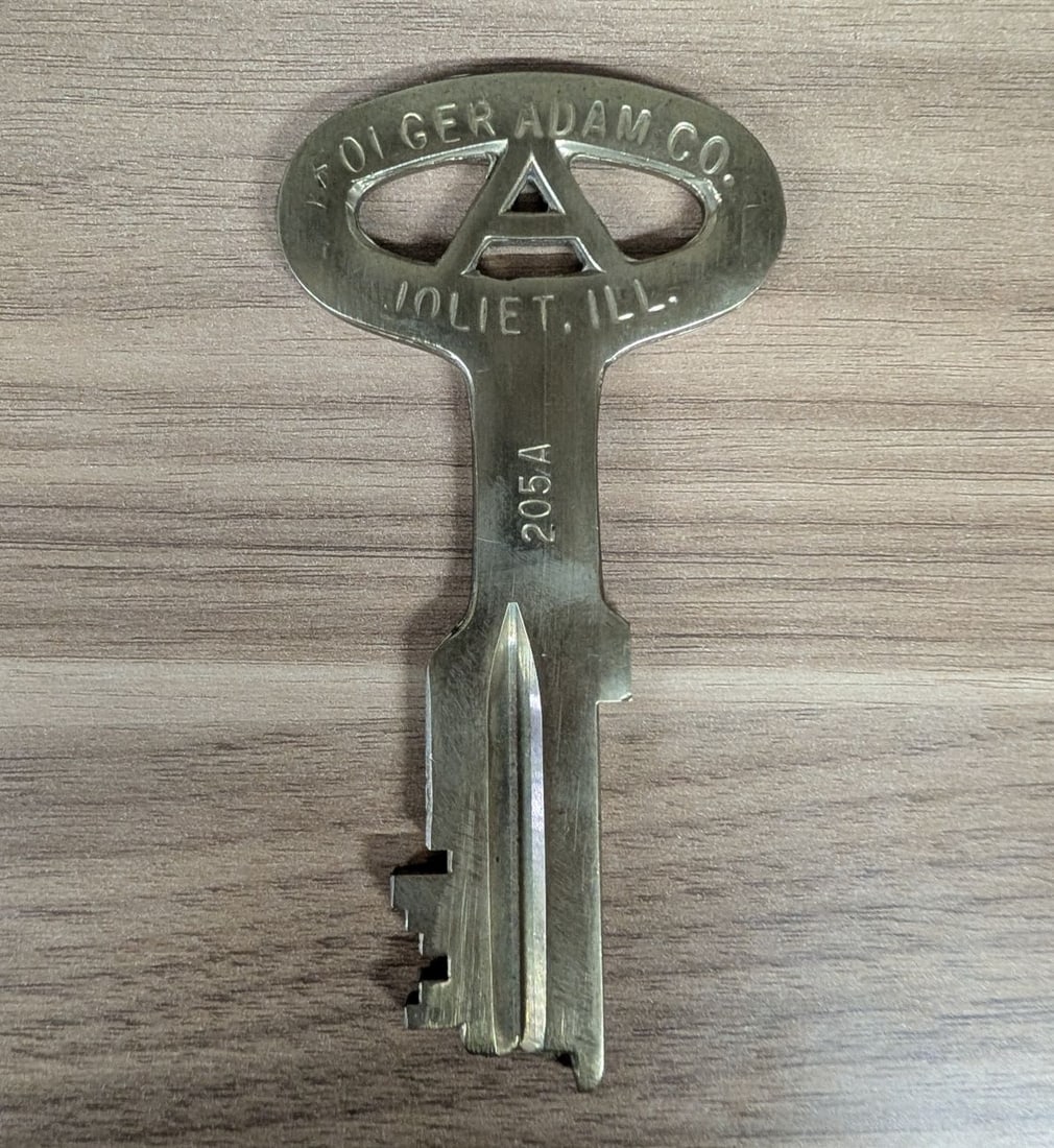 Vintage Folger Adam Co. Joliet, Illinois Prison Key 205A: This is a vintage high-security detention key manufactured by the Folger Adam Co. of Joliet, Illinois. The key is constructed from solid metal with a brass finish. It features a distinctive large oval