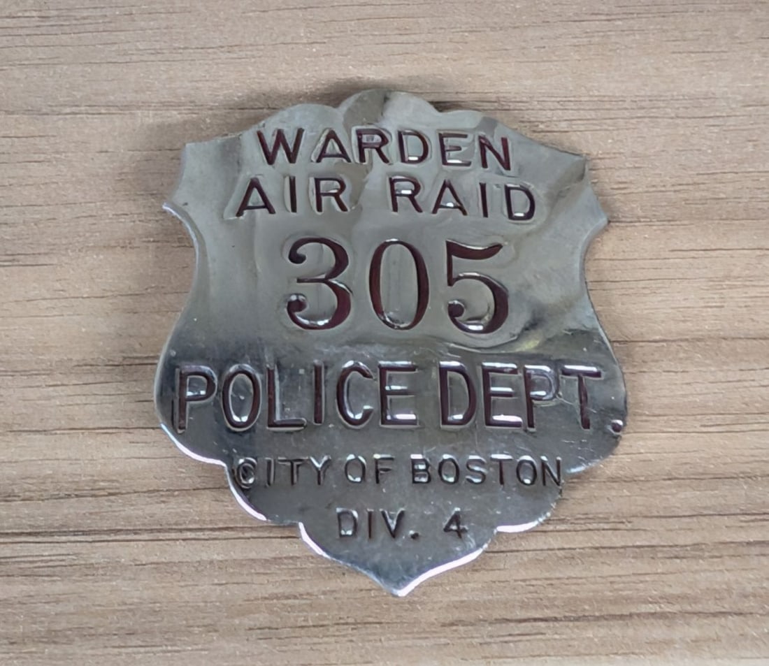 World War II Boston Police Department Air Raid Warden Badge Number 305: A World War II-era Air Raid Warden badge issued by the City of Boston Police Department. The badge is constructed of nickel-plated base metal, likely brass, in a shield shape with a scalloped top and 