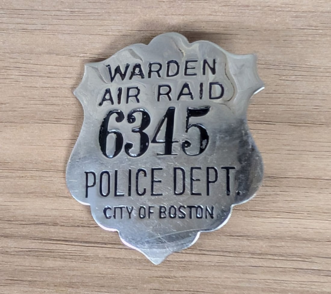 WWII Boston Police Department Air Raid Warden Badge No. 6345: A World War II-era civil defense badge issued to an Air Raid Warden for the City of Boston, Massachusetts. The shield-shaped badge is constructed from plated metal with stamped and black enamel-filled