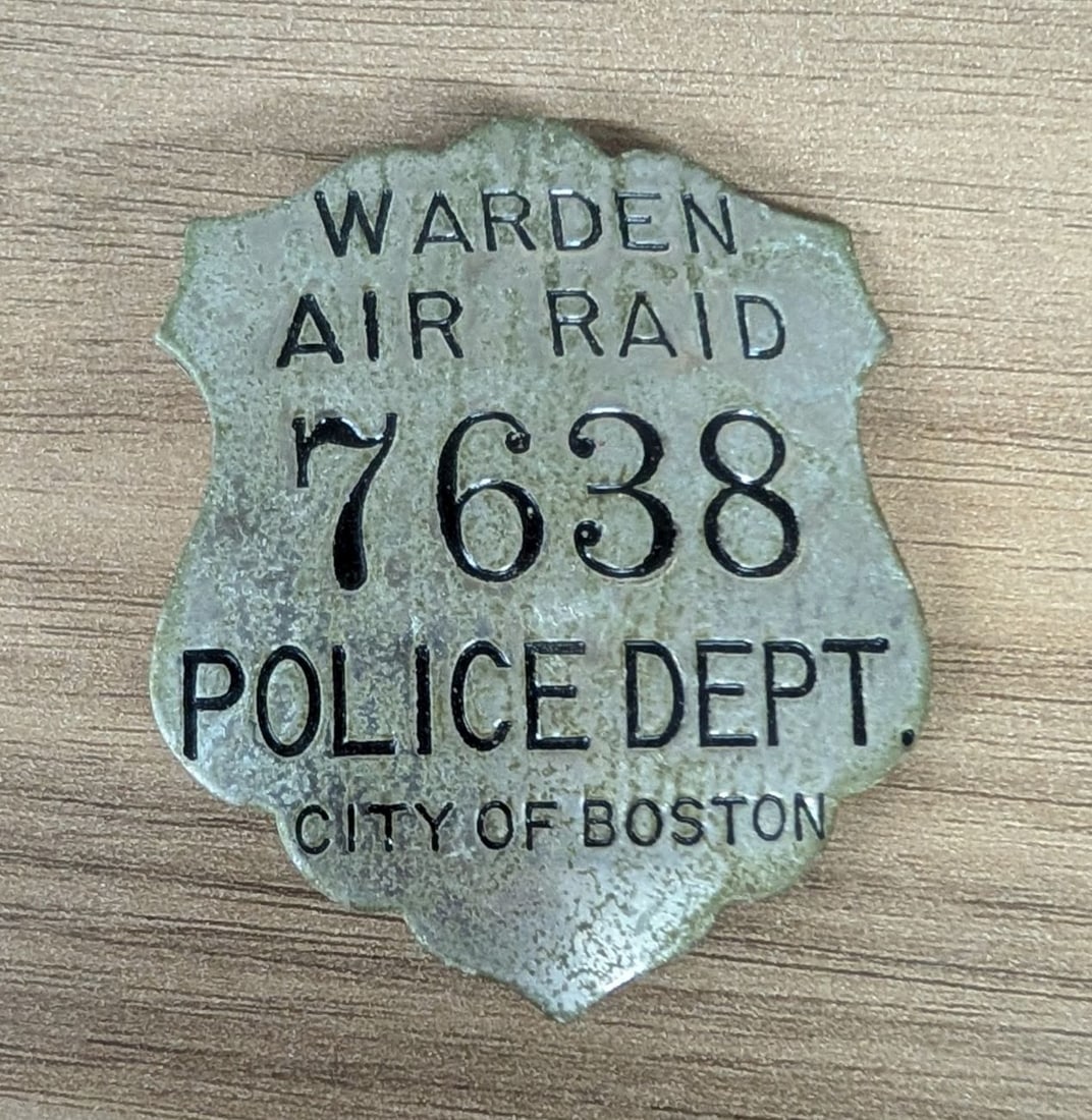 WWII City of Boston Police Department Air Raid Warden Badge No. 7638: Authentic World War II era identification badge issued by the City of Boston Police Department for an Air Raid Warden. The shield-shaped badge is constructed from a silver-toned metal alloy and featur