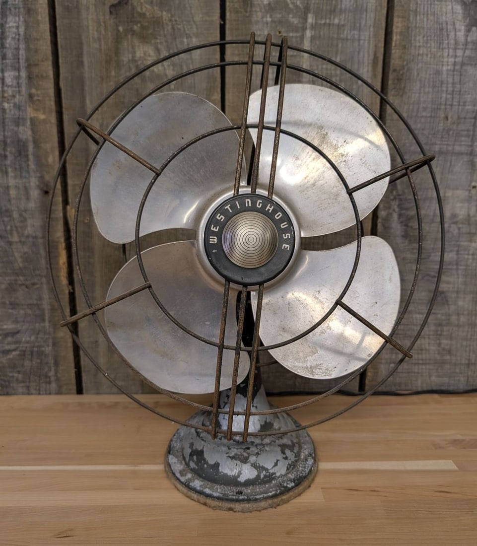 Westinghouse Mid-Century Streamline Moderne Electric Desk Fan: Westinghouse electric desk fan featuring a streamline moderne teardrop-shaped motor housing. The unit is constructed with a painted cast metal base and motor housing, four wide-profile aluminum blades