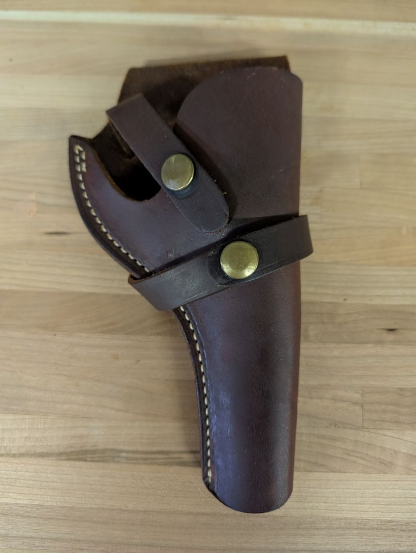 Brauer Bros Mfg Co Model H19 Leather Holster: This lot features a dark brown leather handgun holster produced by Brauer Bros Mfg Co of St. Louis. The holster is constructed from a single piece of leather with a white contrast stitched seam and fe