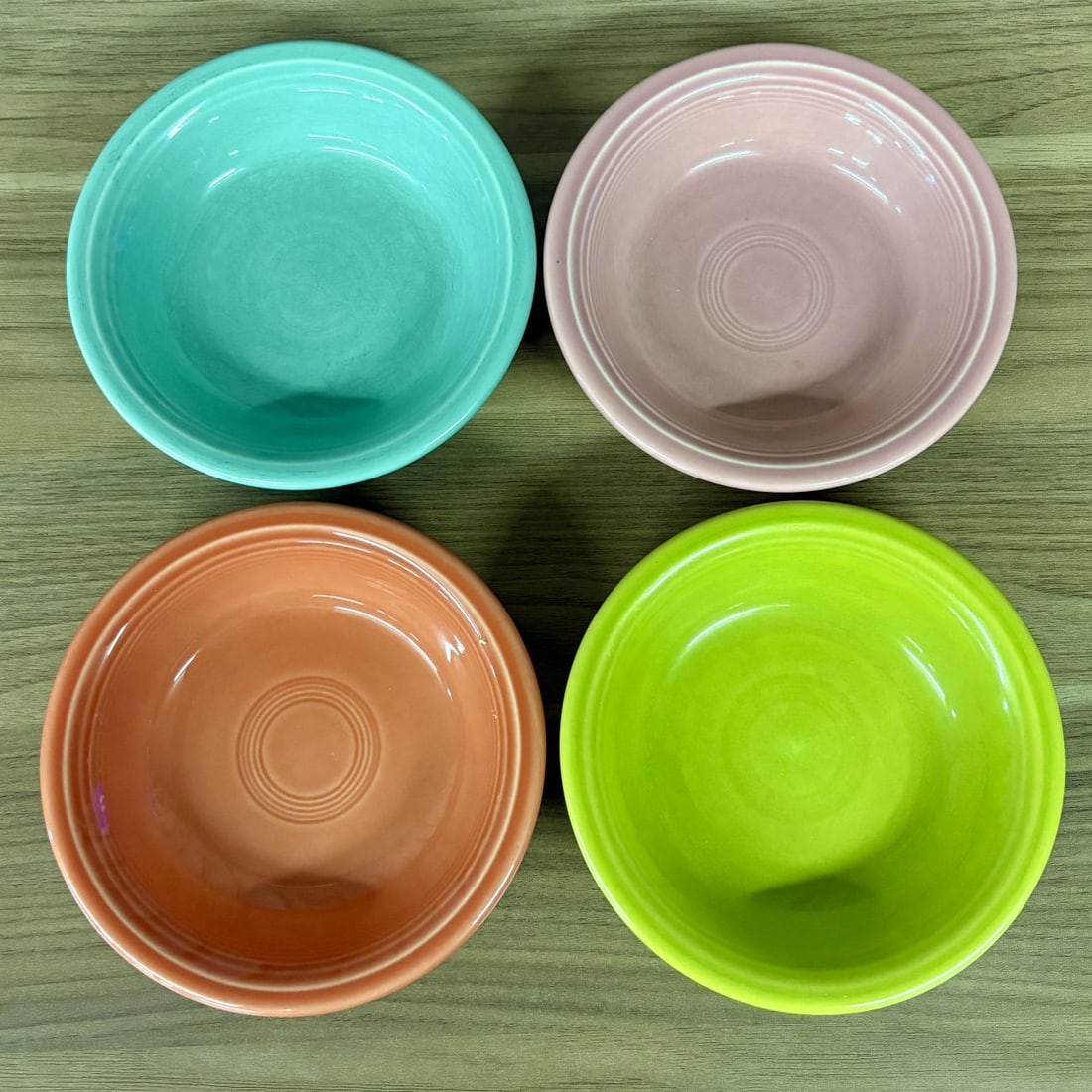 A Group of Homer Laughlin Fiesta Glazed Earthenware Bowls: A group of four glazed earthenware bowls manufactured by the Homer Laughlin China Company as part of the Fiesta line. These small round bowls, often categorized as fruit or dessert bowls, feature sign