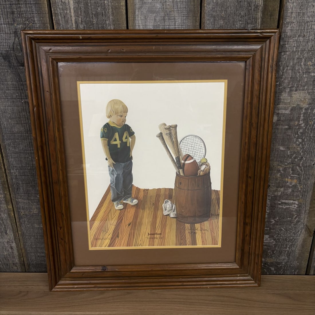 Bob Dale Green Jonathan Growing Up Limited Edition Signed Lithograph: This limited edition lithographic print on paper is titled Jonathan Growing Up by artist Bob Dale Green. The composition features a young boy in a green and yellow football jersey numbered 44 standing