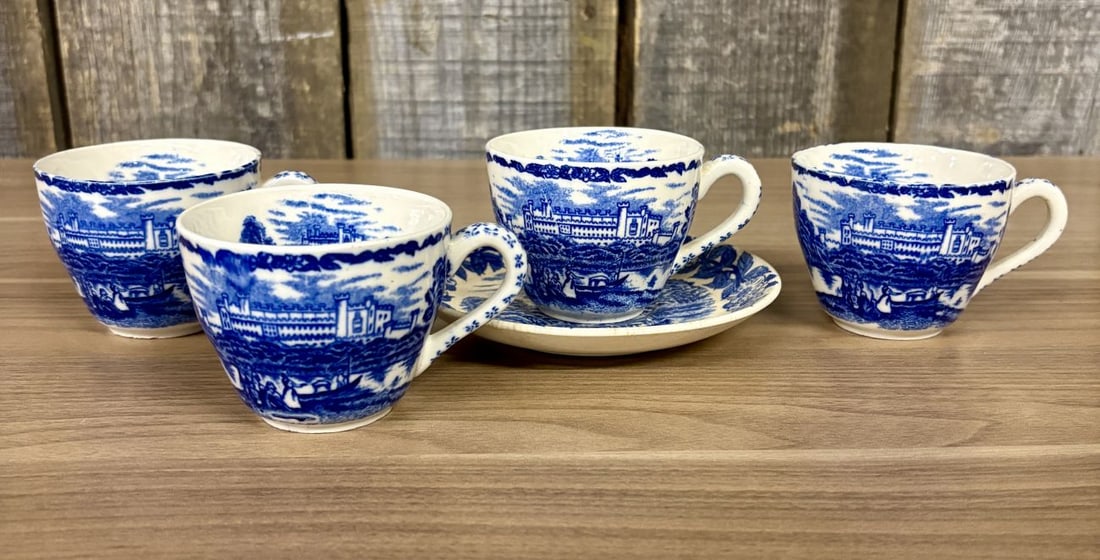 Four Blue and White Transfer-Printed Earthenware Teacups and One Saucer Featuring Windsor Castle: This set consists of four teacups and one matching saucer made of earthenware. Each piece is decorated with a blue transfer-printed landscape pattern. The primary scene depicts Windsor Castle situated