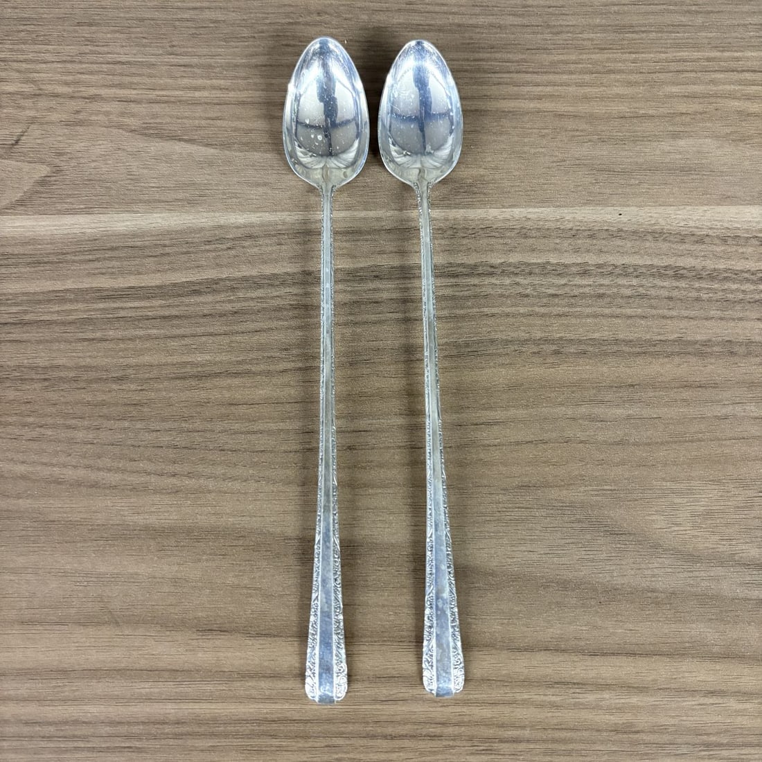 A Pair of Towle Sterling Silver Iced Tea Spoons in the Candlelight Pattern: This pair of sterling silver iced tea spoons was produced by Towle Silversmiths in the Candlelight pattern, which was introduced in 1934. The spoons feature elongated stems and oval bowls designed for