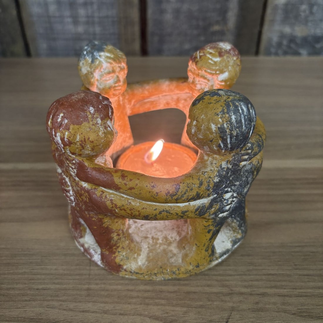 Mexican Pottery Circle of Friends Figural Candle Holder: A Circle of Friends figural tealight candle holder constructed from textured terracotta. The design features four stylized human figures standing in a circular formation with arms linked around one an