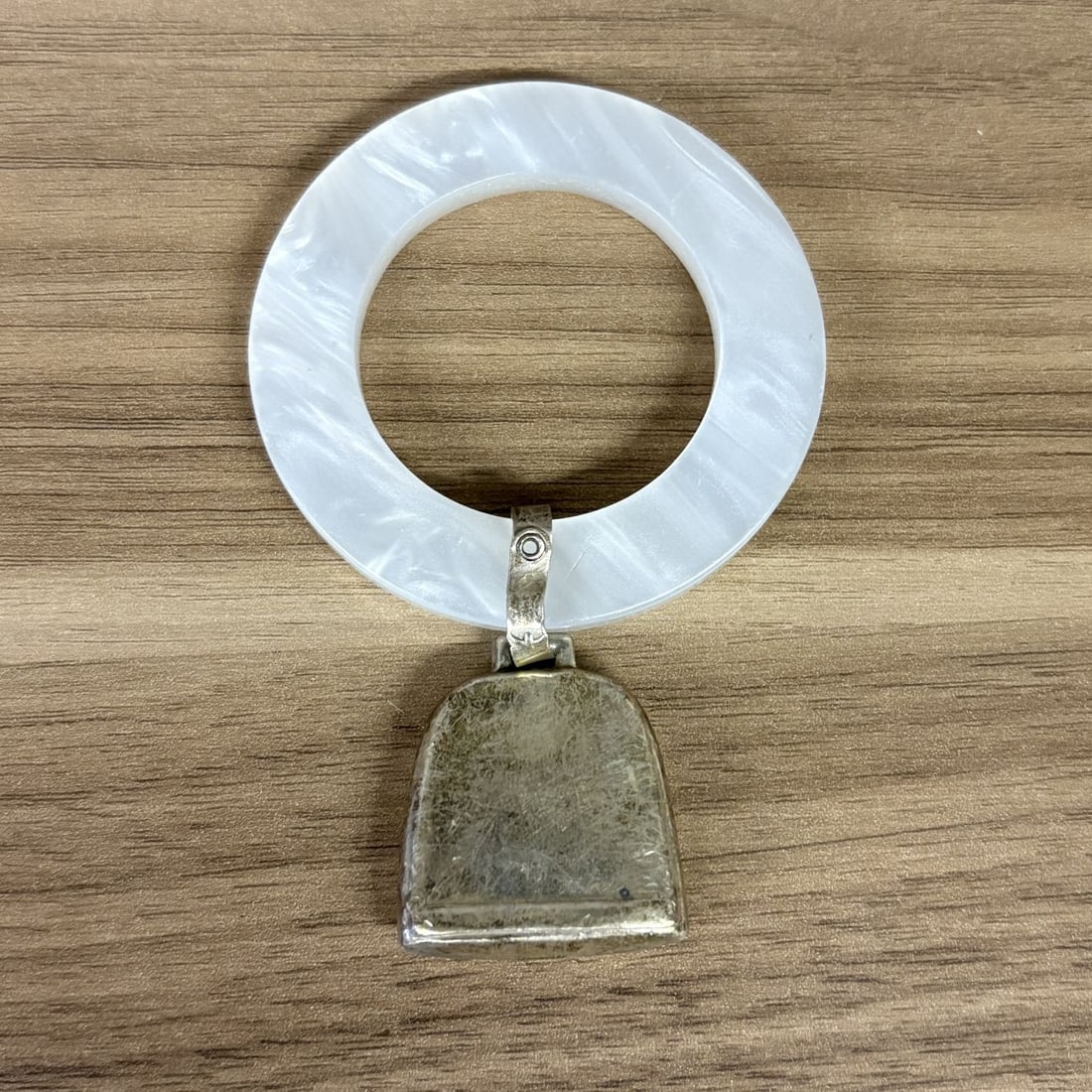 Webster Baby Bell Rattle Teething Ring: Webster Sterling Company baby bell rattle and teething ring. The item features a hollow, arch-shaped bell attached via a silver-tone metal bail to a pearlescent white ring. The ring is composed of a m