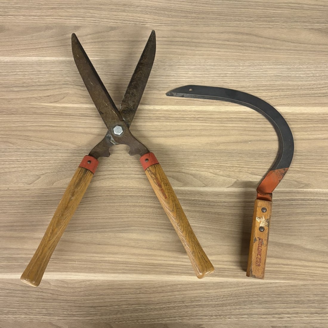 Two Vintage Cyclone Garden Tools Including Hedge Shears and Grass Sickle: Manufactured by Cyclone, this lot consists of two vintage handheld garden tools: a pair of long-handled hedge shears and a hand sickle, also known as a grass hook. The hedge shears are designed with f