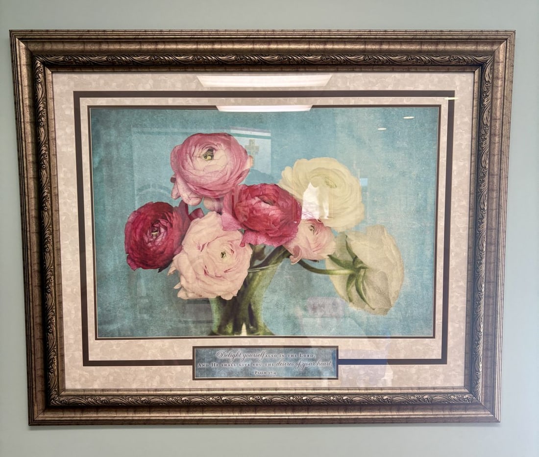 Framed Floral Still Life Print with Ranunculus and Psalm 37:4: A large-format decorative digital print featuring a floral still life. The composition depicts a bouquet of ranunculus blossoms in shades of white, pink, and burgundy, arranged in a glass vessel again