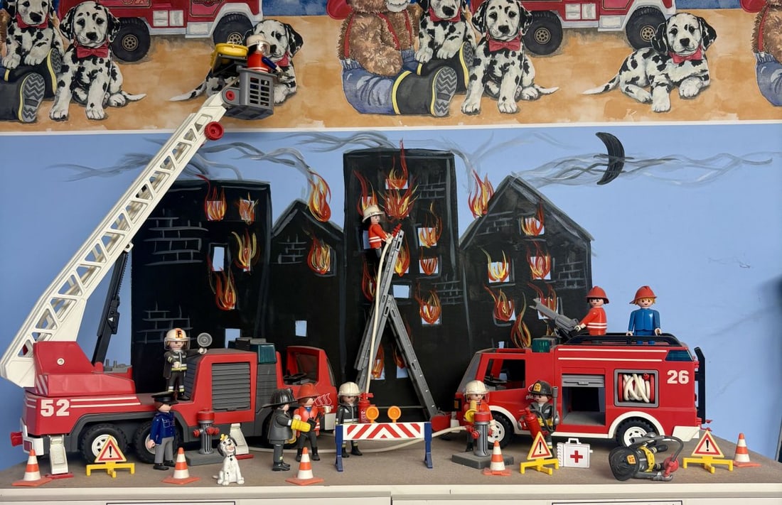 A Collection of Playmobil Fire Department Vehicles, Figures, and Accessories: This collection of molded plastic toys features a fire department theme, presented as a curated diorama. The lot includes two large vehicles: a ladder truck and a pumper truck. The ladder truck featur