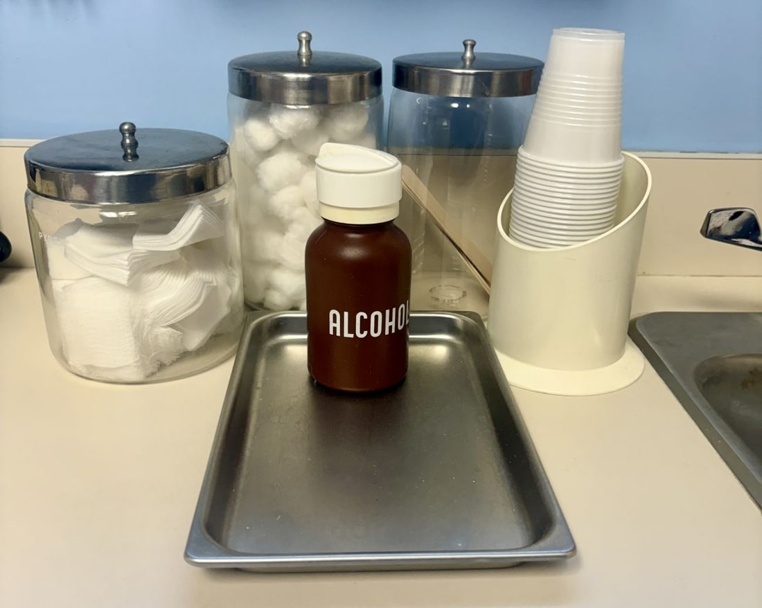 A Collection of Pyrex Glass Storage Jars and Medical Office Supplies: An assortment of medical office storage and dispensing equipment. The collection includes three cylindrical glass jars, each topped with a polished metal lid featuring a ball-shaped finial. One glass
