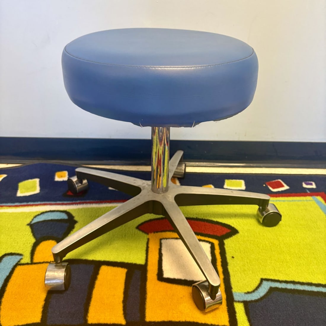 Blue Vinyl Padded Pneumatic Medical Stool on Five-Point Rolling Base: This professional rolling stool, designed for use in medical or laboratory settings, features a round seat with thick padding upholstered in blue vinyl. The seat is supported by a central