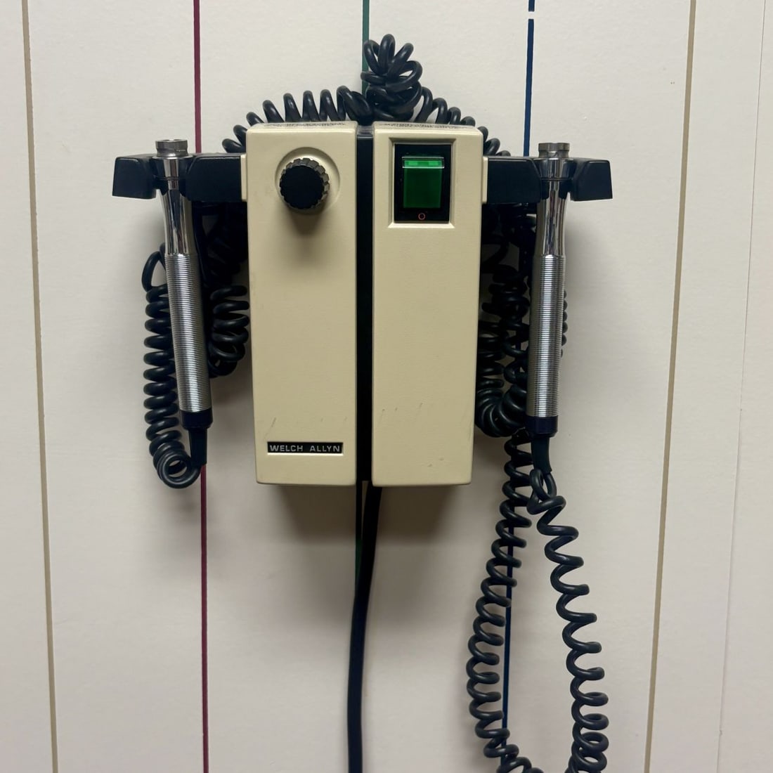 Welch Allyn Wall-Mounted Medical Transformer with Dual Handles: This medical instrument is a wall-mounted transformer unit manufactured by Welch Allyn. The device features a beige composite plastic housing consisting of two vertical rectangular modules joined at t